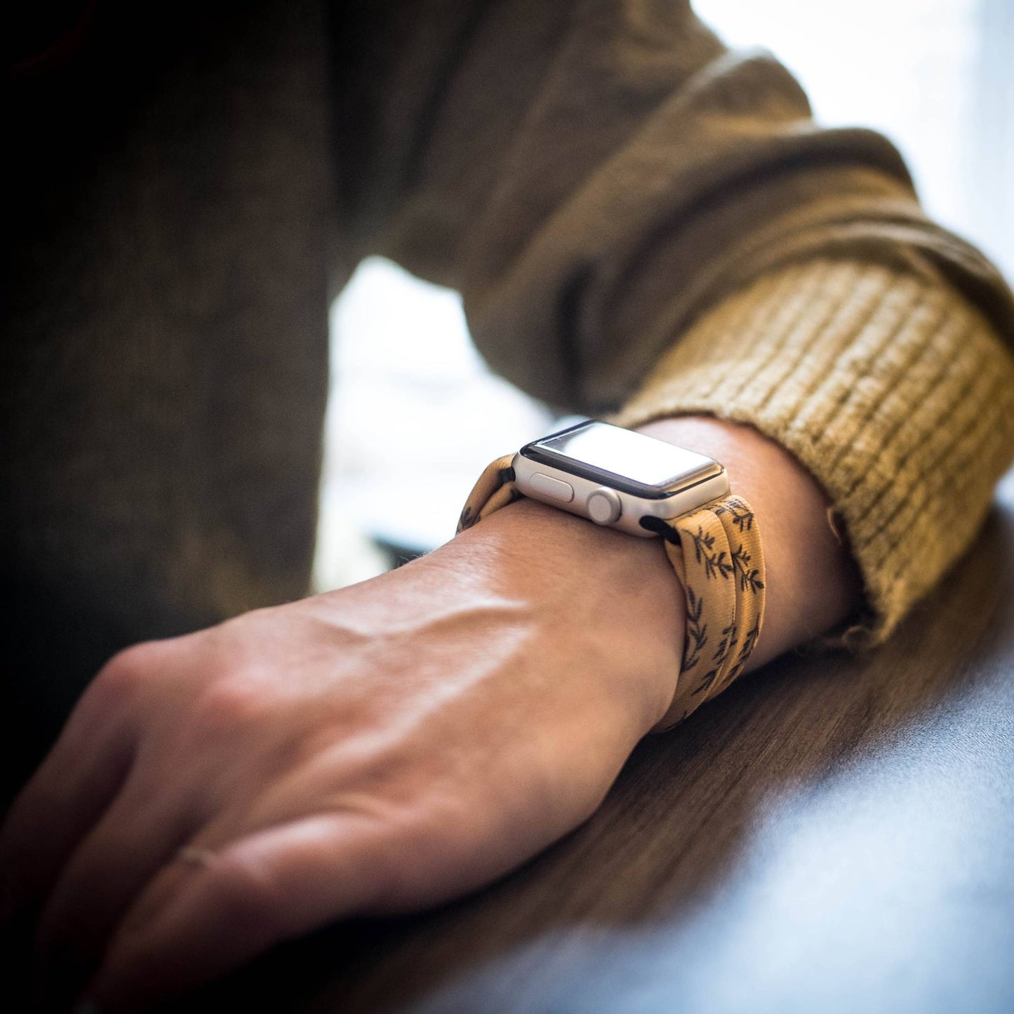 Golden Laurel Yoga Band® featuring a delicate black laurel leaf print on a vibrant goldenrod fabric. A breathable, stretchy watch strap with a patent-pending design compatible with Apple Watch, Fitbit, and Samsung Galaxy models.
