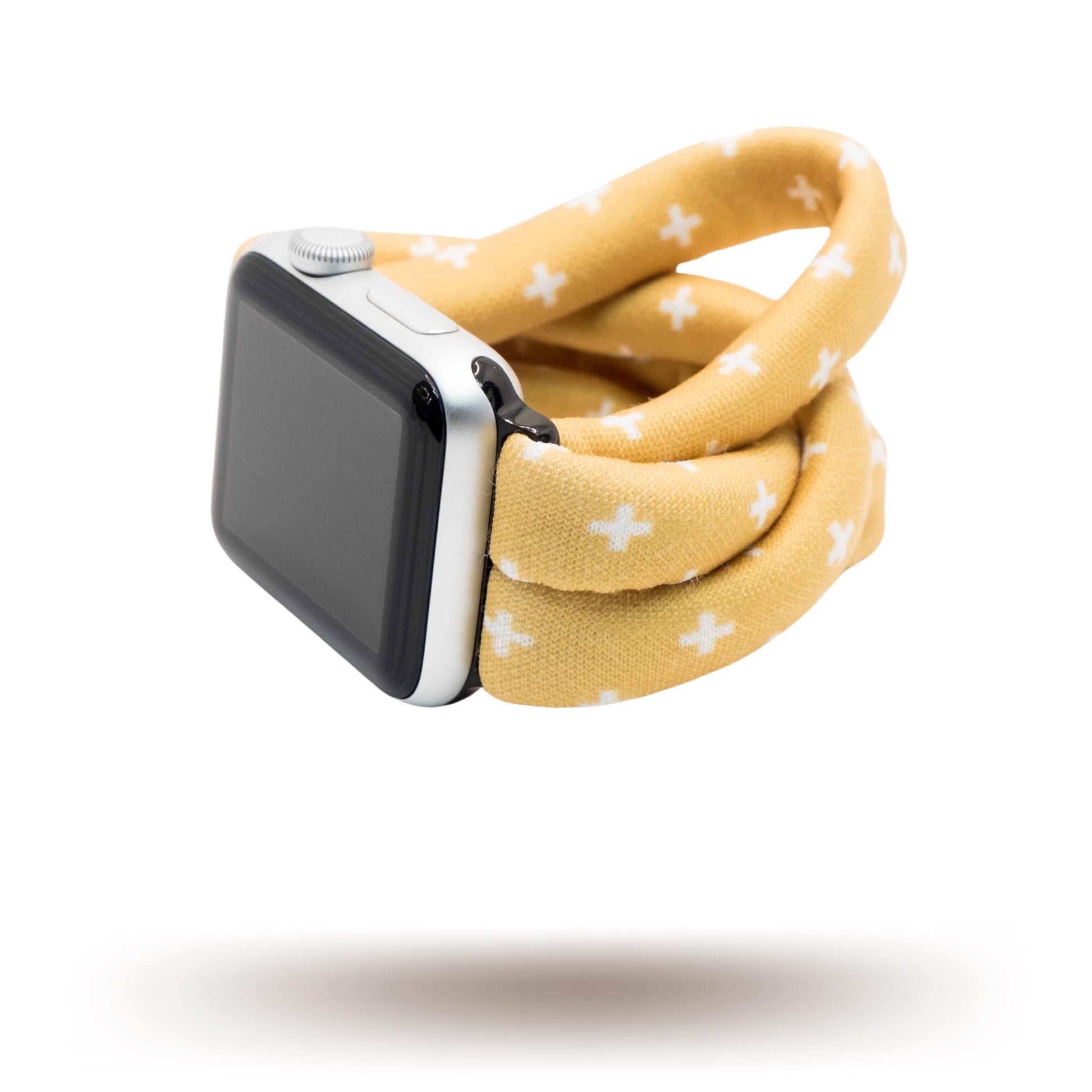 Golden Plus Yoga Band® featuring a white plus sign print on a golden-tan fabric background. A breathable, stretchy watch strap with a patent-pending design compatible with Apple Watch, Fitbit, and Samsung Galaxy models.